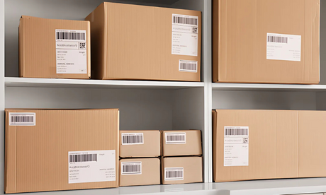 Multiple cardboard packages with barcode tracking labels arranged on white shelves for organized storage and shipping.
