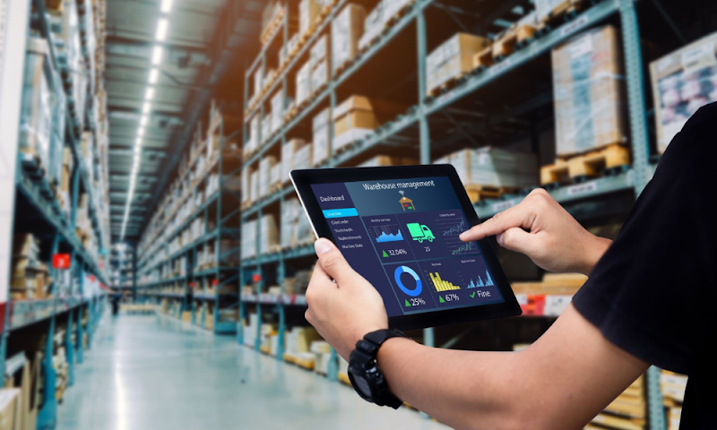 Warehouse staff using a tablet to monitor inventory and performance via an order management system.